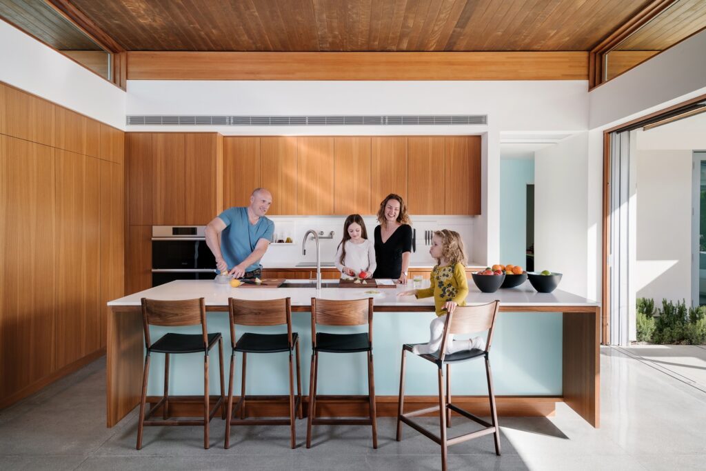 Una familia prepara comida en una isla de cocina.