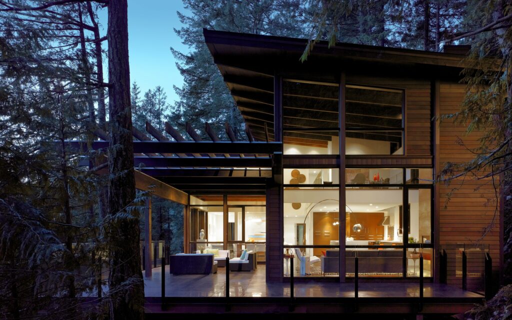 View of a modern wooden home lit from within at dusk