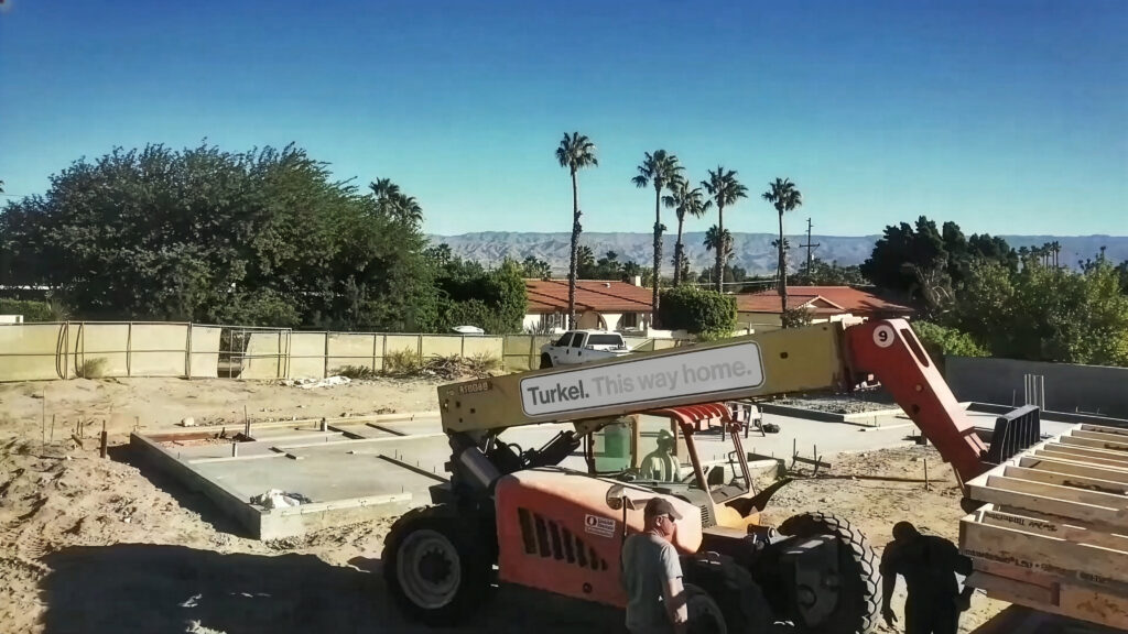 Lull with the Turkel Design logo assembles a prefab home in the desert