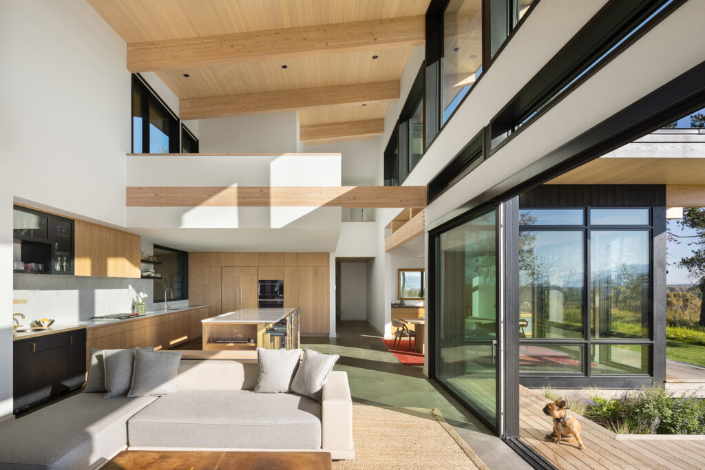 Double-height great room of a modern home with living, dining, and kitchen areas, and a loft above