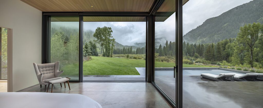 Main-level primary suite in a modern mountain home with a view of the pool