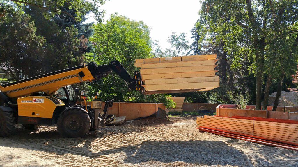 A lull lifts flat panels at the site of a prefab home