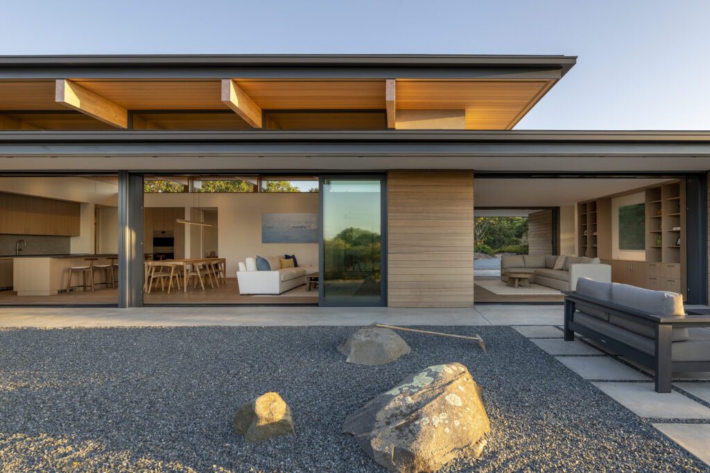 View of the open great room of a single-level modern home with a rock garden in the foreground